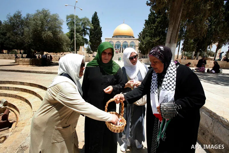 A Muslim woman gives candy during a celebration of the Islamic holiday of Isra Mi'raj in the Al-Aqsa mosque, in the Jerusalem old city, on June 17, 2012. The holiday marks what Muslims believe is Prophet Mohammad's journ...