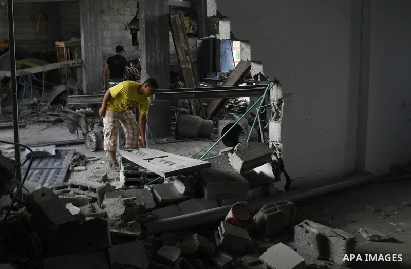 Palestinians survey a destroyed metal workshop after an Israeli air strike in Rafah, in the southern Gaza Strip June 18, 2012. Overnight on Sunday, Israeli aircraft carried out a series of strikes in the Gaza Strip in re...