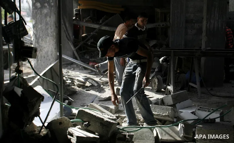 Palestinians survey a destroyed metal workshop after an Israeli air strike in Rafah, in the southern Gaza Strip June 18, 2012. Overnight on Sunday, Israeli aircraft carried out a series of strikes in the Gaza Strip in re...