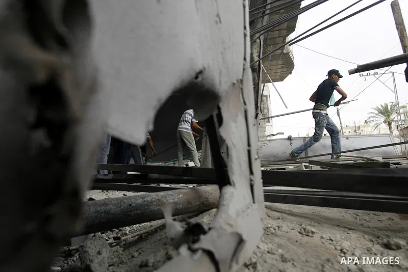 Palestinians survey a destroyed metal workshop after an Israeli air strike in Rafah, in the southern Gaza Strip June 18, 2012. Overnight on Sunday, Israeli aircraft carried out a series of strikes in the Gaza Strip in re...