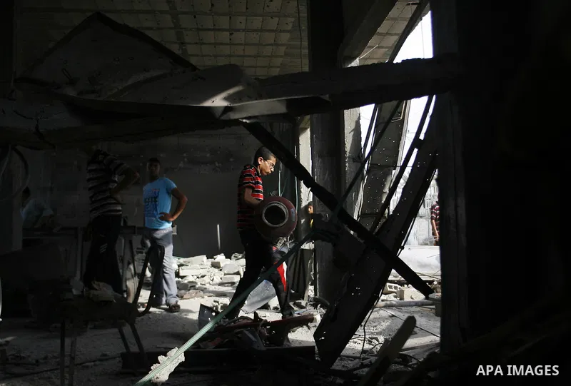 Palestinians survey a destroyed metal workshop after an Israeli air strike in Rafah, in the southern Gaza Strip June 18, 2012. Overnight on Sunday, Israeli aircraft carried out a series of strikes in the Gaza Strip in re...