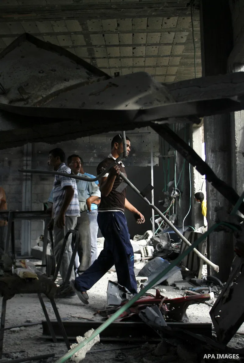 Palestinians survey a destroyed metal workshop after an Israeli air strike in Rafah, in the southern Gaza Strip June 18, 2012. Overnight on Sunday, Israeli aircraft carried out a series of strikes in the Gaza Strip in re...