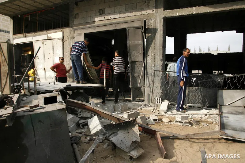 Palestinians survey a destroyed metal workshop after an Israeli air strike in Rafah, in the southern Gaza Strip June 18, 2012. Overnight on Sunday, Israeli aircraft carried out a series of strikes in the Gaza Strip in re...