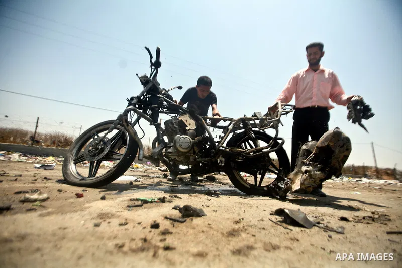 Palestinians look at a burnt out motorcycle that was destroyed in an Israeli air strike on north Gaza on June 18, 2012 killing two Palestinian men that were riding the motorbike near the Israeli border at the time. Witne...
