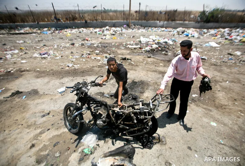 Palestinians look at a burnt out motorcycle that was destroyed in an Israeli air strike on north Gaza on June 18, 2012 killing two Palestinian men that were riding the motorbike near the Israeli border at the time. Witne...