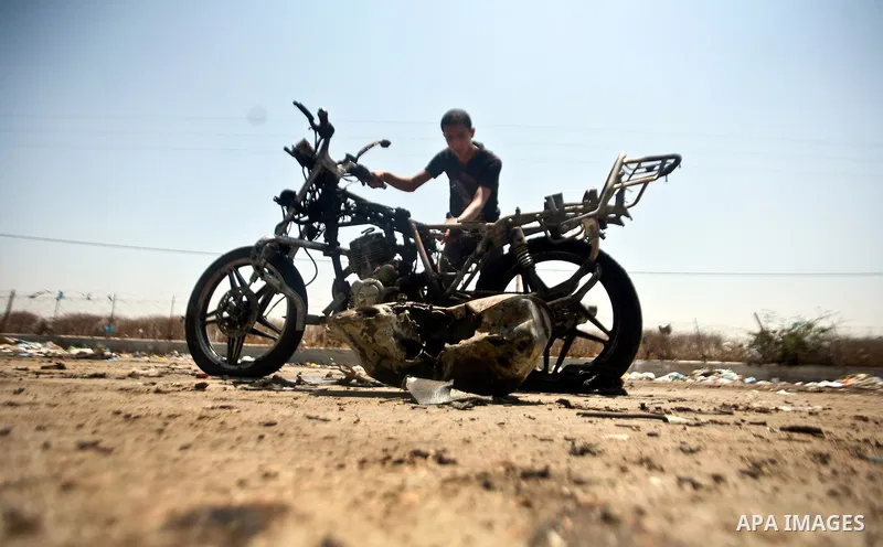 Palestinians look at a burnt out motorcycle that was destroyed in an Israeli air strike on north Gaza on June 18, 2012 killing two Palestinian men that were riding the motorbike near the Israeli border at the time. Witne...