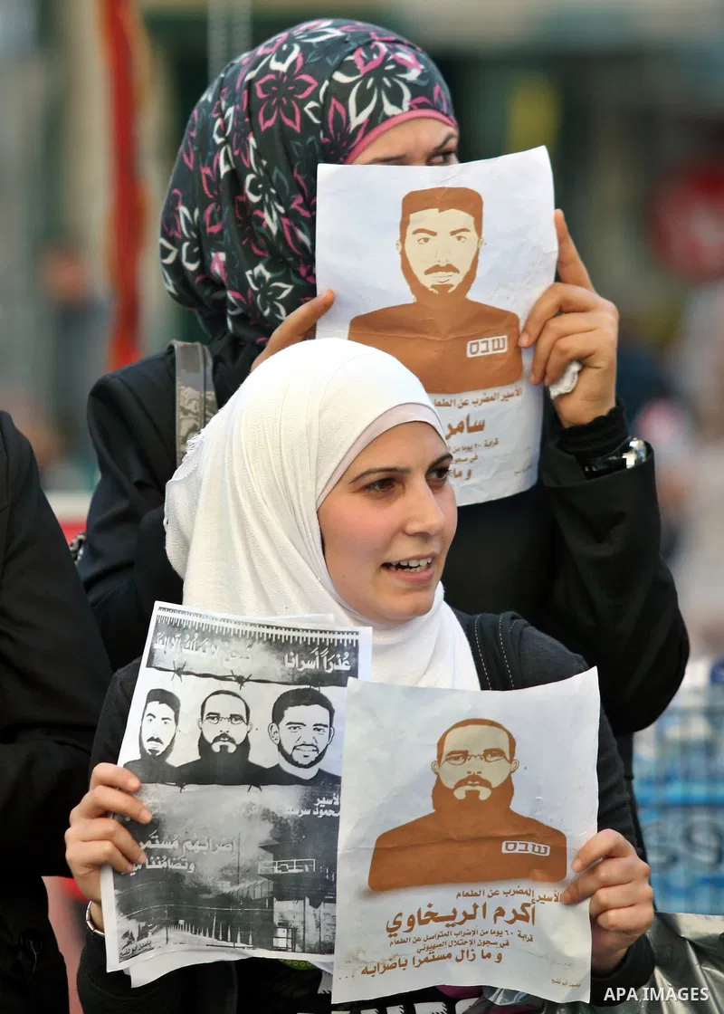 Palestinian protestors hold pictures of Palestinian prisoner Mahmoud Al-Sarsak, who is still refusing food for 96 days after a deal was made to end a mass prisoner hunger strike, during a demonstration in support him, in...