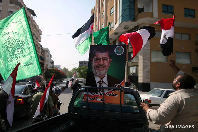 Palestinian Hamas supporters hold up Egyptian flags and the poster of the Muslim Brotherhood's presidential candidate Mohammed Morsi as they celebrate in the streets of Gaza City, 18 June 2012. Egypt's Muslim Brotherhood...