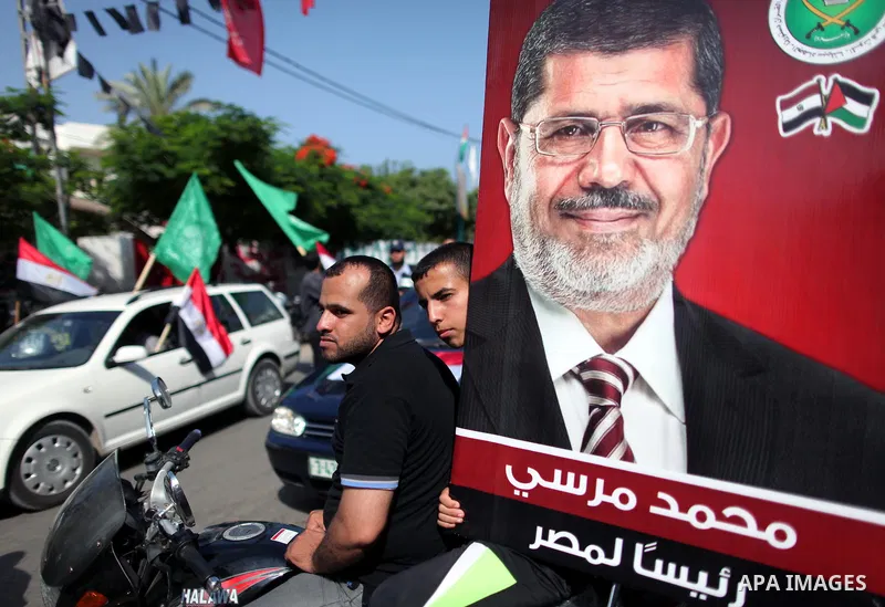 Palestinian Hamas supporters hold up Egyptian flags and the poster of the Muslim Brotherhood's presidential candidate Mohammed Morsi as they celebrate in the streets of Gaza City, 18 June 2012. Egypt's Muslim Brotherhood...