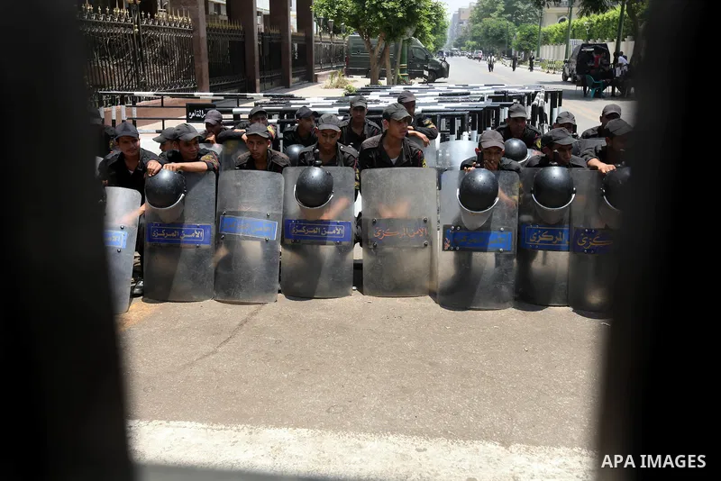 Egyptian riot police sit outside the parliament as protesters gather in Cairo, on June 19, 2012, after the Supreme Council of the Armed Forces (SCAF) issued a constitutional declaration on June 17, claiming legislative p...