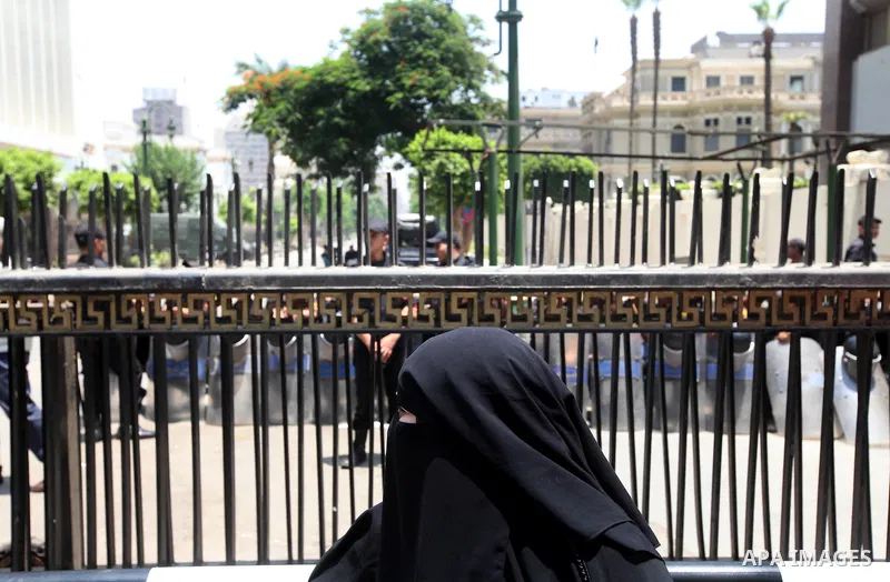 An Egyptian woman stands in front of riot police blocking the access to the street of the parliament in Cairo, Egypt, 09 June 2012. A new constitutional document issued by the Supreme Council of the Armed Forces (SCAF),...
