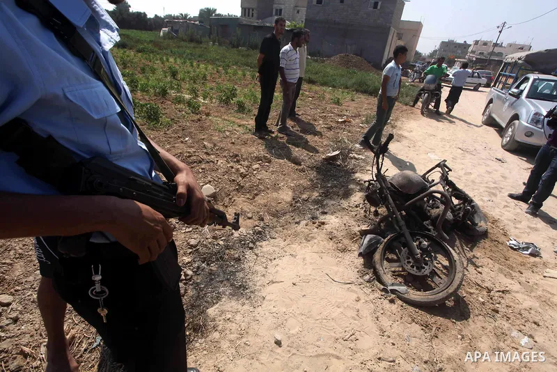 A Hamas policeman stands near a motorcycle that was hit in an Israeli air strike in Dir al-Balah in the central Gaza Strip June 19, 2012. An Israeli army statement said the Israeli air force targeted Palestinian militant...