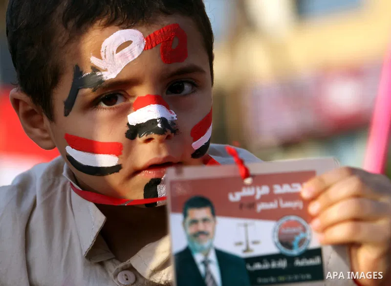 An Egyptian child hold a picture of Muslim Brotherhood presidential candidate Mohammed Mursi in Cairo's Tahrir Square on June 19, 2012 during a protest against the ruling military's bid to grab new powers, as both presid...