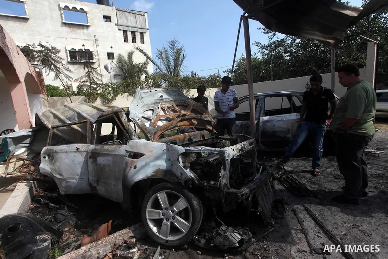 Palestinians are seen through a burnt cars of the potato outside a house after an Israeli air strike in Dir al-Balah in the central in the Gaza Strip June 20, 2012. The Israeli military said it had struck militant sites...