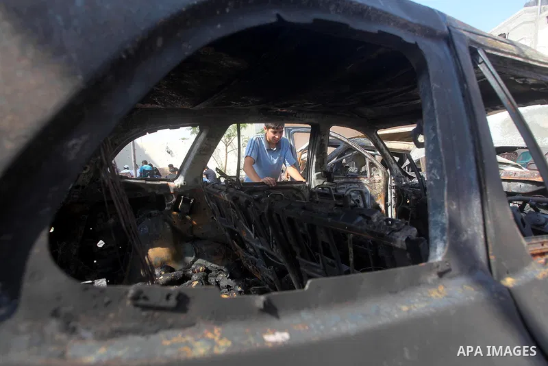 Palestinians are seen through a burnt cars of the potato outside a house after an Israeli air strike in Dir al-Balah in the central in the Gaza Strip June 20, 2012. The Israeli military said it had struck militant sites...