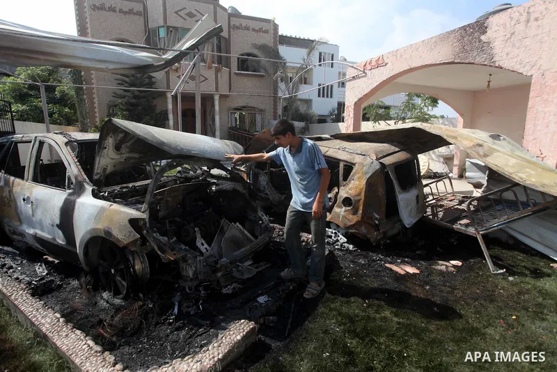 Palestinians are seen through a burnt cars of the potato outside a house after an Israeli air strike in Dir al-Balah in the central in the Gaza Strip June 20, 2012. The Israeli military said it had struck militant sites...