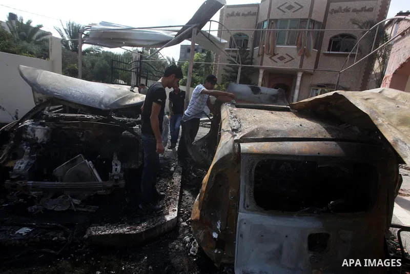 Palestinians are seen through a burnt cars of the potato outside a house after an Israeli air strike in Dir al-Balah in the central in the Gaza Strip June 20, 2012. The Israeli military said it had struck militant sites...