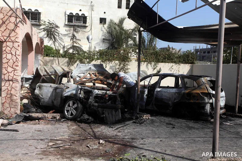 Palestinians are seen through a burnt cars of the potato outside a house after an Israeli air strike in Dir al-Balah in the central in the Gaza Strip June 20, 2012. The Israeli military said it had struck militant sites...