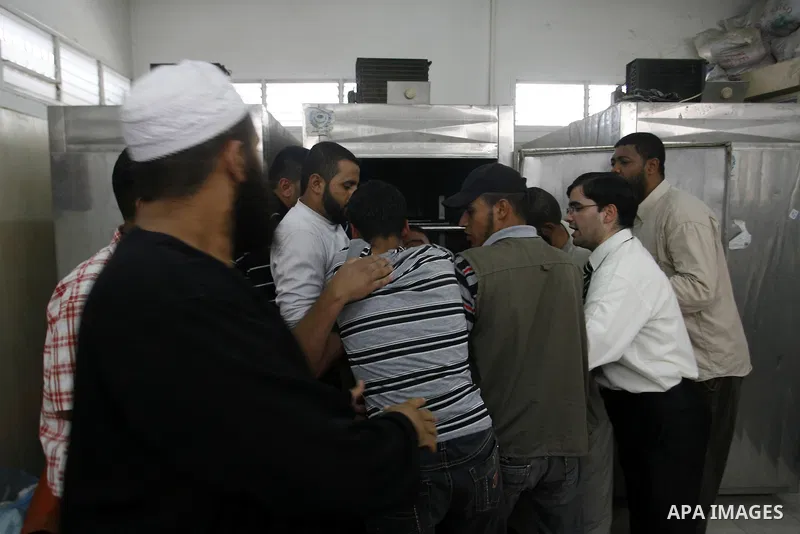 Palestinians look at the body of 21-year-old Ghaleb Ermilat, , at the morgue in the Al Najar hospital in Rafah, in the Gaza Strip on June 20, 2012. There was no let-up in rocket fire from Gaza with at least 10 hitting th...