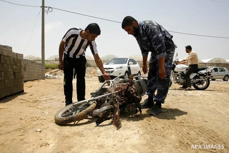 Palestinians look at the blood stained motorcycle riden by 21-year-old Ghaleb Ermilat, when he was killed in an Israeli military strike in Rafah, in the Gaza Strip on June 20, 2012. According to the Isreali military, the...