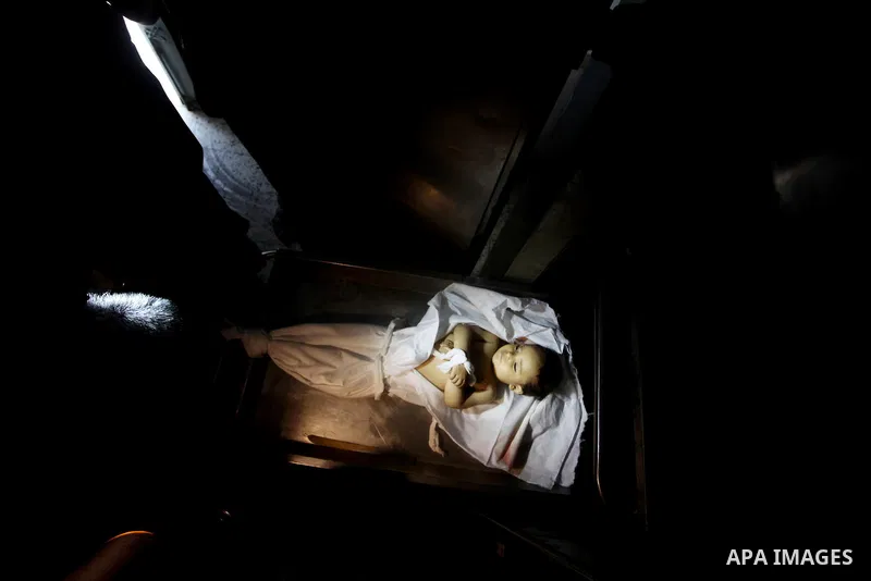 A Palestinian looks at the body of two-year-old girl, Hadeel al-Hadad, at the morgue in the al-Shifa hospital in Gaza City on June 20, 2012. There was no let-up in rocket fire from Gaza with at least 10 hitting the Jewis...