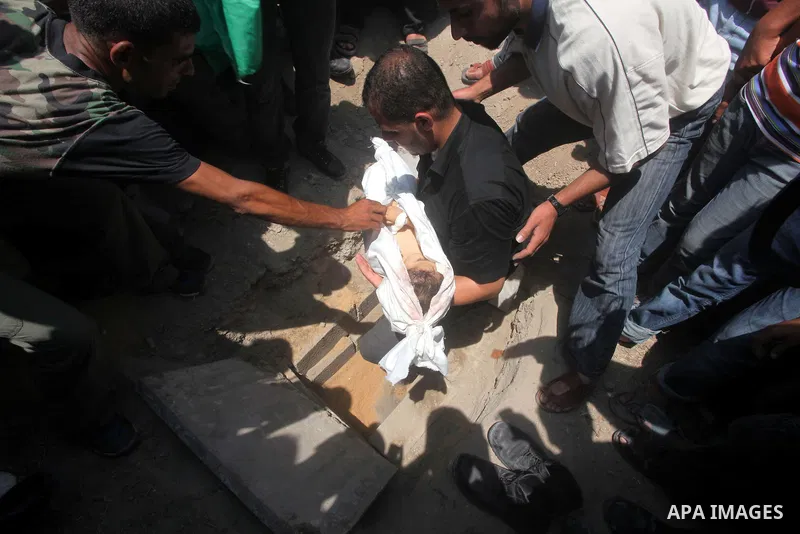 A Palestinian relative buries the body of two-year-old Hadeel al Hadad, after her funeral in Gaza City, Wednesday, June 20, 2012. Gaza health official Adham Abu Salmia said an explosion in a house killed al-Hadad and inj...