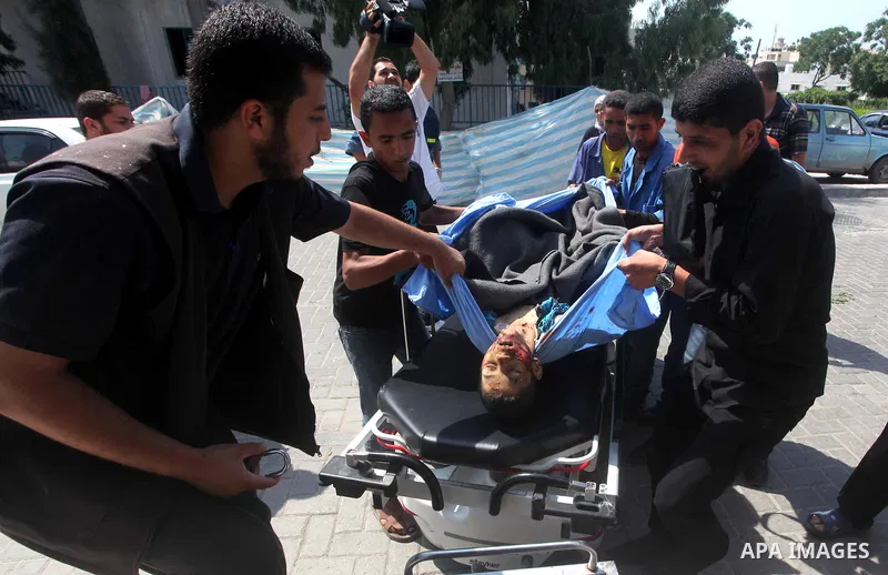 Palestinian men carry the body of Moamen al-Adam, 14, to the morgue of Al-Shifa hospital in Gaza City on June 20, 2012 after he was killed and his father Zohde Al-Dam in an Israeli air strike raising to eight the number...