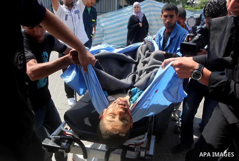 Palestinian men carry the body of Moamen al-Adam, 14, to the morgue of Al-Shifa hospital in Gaza City on June 20, 2012 after he was killed and his father Zohde Al-Dam in an Israeli air strike raising to eight the number...