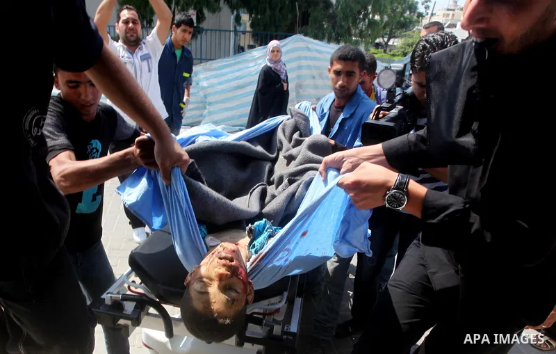 Palestinian men carry the body of Moamen al-Adam, 14, to the morgue of Al-Shifa hospital in Gaza City on June 20, 2012 after he was killed and his father Zohde Al-Dam in an Israeli air strike raising to eight the number...