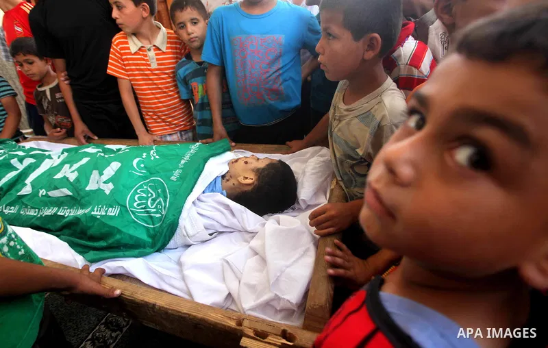 Friends of 14-year old Palestinian Moamen al-Adam, who was killed in an Israeli air strike the day before, bids farewell to him during his funeral procession in Gaza city on June 21, 2012. The latest attacks follow three...