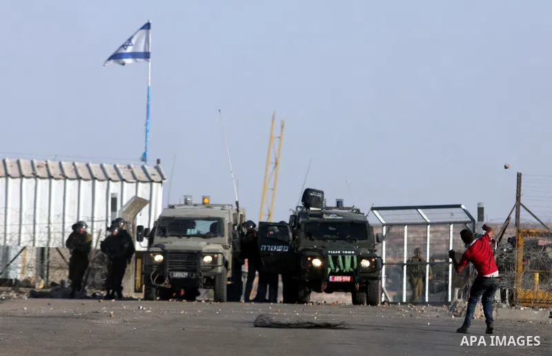 A Palestinian protestor throws stones using a sling shot during clashes with Israeli police following a demonstration outside Ofer prison, near the West Bank city of Ramallah, in solidarity with Palestinian prisoners bei...
