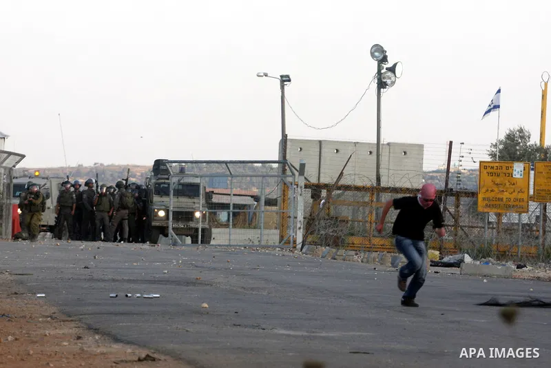 A Palestinian protestor takes cover during clashes with Israeli police following a demonstration outside Ofer prison, near the West Bank city of Ramallah, in solidarity with Palestinian prisoners being held in Israeli ja...