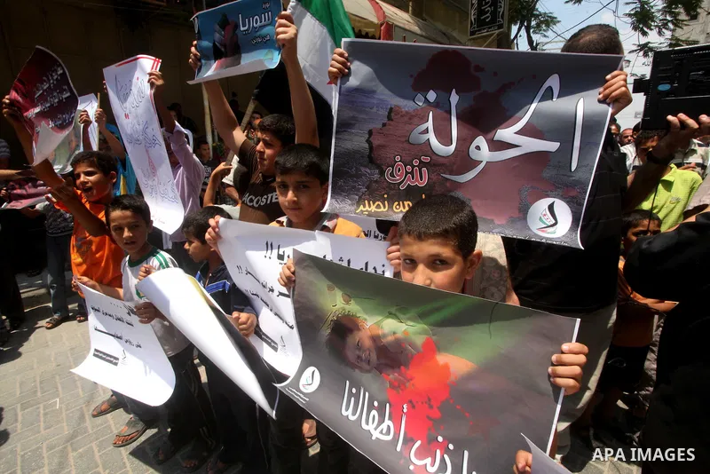 Palestinian children hold a Syrian revolution flag during a protest against Syria's President Bashar al-Assad and in support of Syrian civilians at Nusseirat refugee camp in the central Gaza Strip on June 22, 2012. The F...