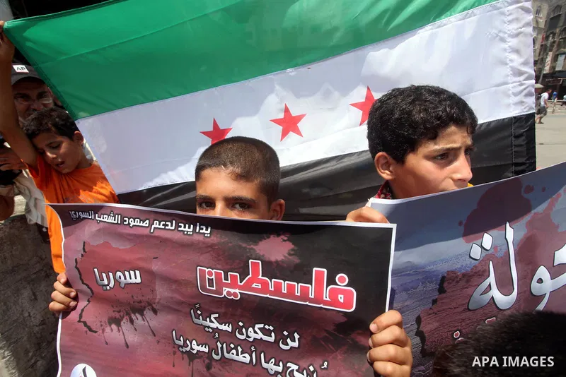 Palestinian children hold a Syrian revolution flag during a protest against Syria's President Bashar al-Assad and in support of Syrian civilians at Nusseirat refugee camp in the central Gaza Strip on June 22, 2012. The F...