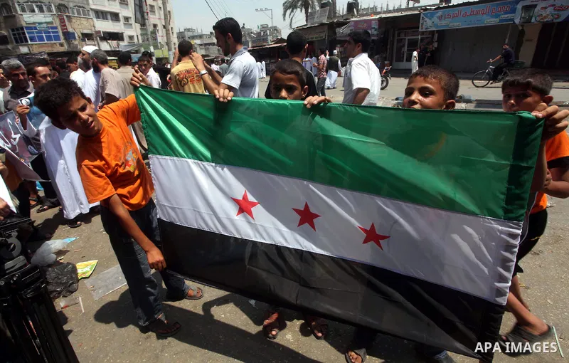 Palestinian children hold a Syrian revolution flag during a protest against Syria's President Bashar al-Assad and in support of Syrian civilians at Nusseirat refugee camp in the central Gaza Strip on June 22, 2012. The F...
