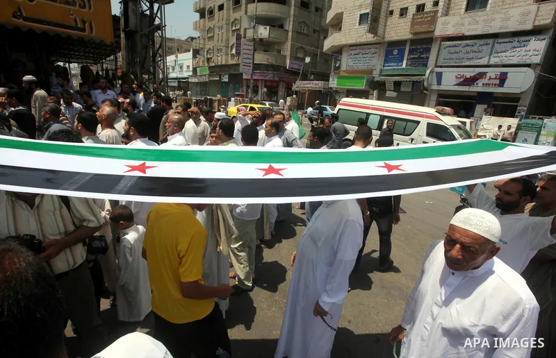 Palestinians hold a Syrian revolution flag during a protest against Syria's President Bashar al-Assad and in support of Syrian civilians at Nusseirat refugee camp in the central Gaza Strip on June 22, 2012. The French fo...