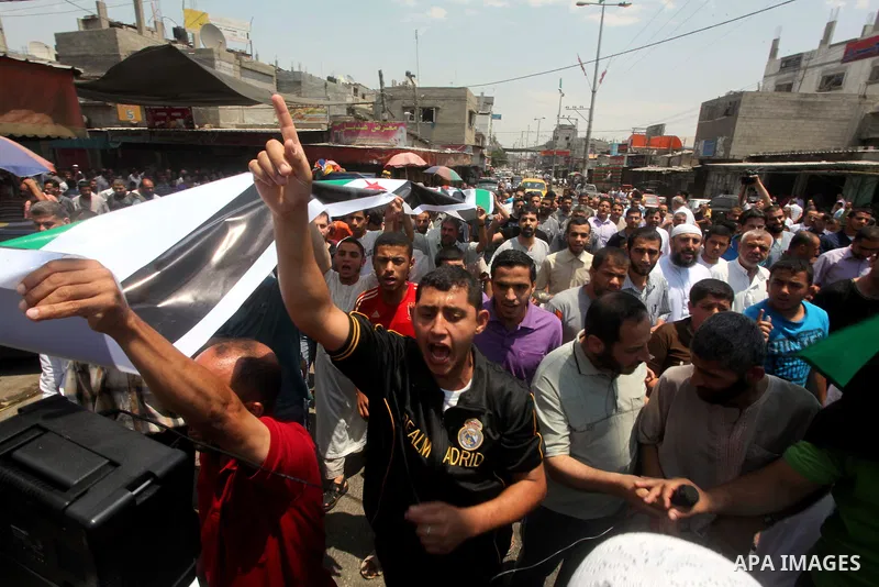 Palestinians hold a Syrian revolution flag during a protest against Syria's President Bashar al-Assad and in support of Syrian civilians at Nusseirat refugee camp in the central Gaza Strip on June 22, 2012. The French fo...