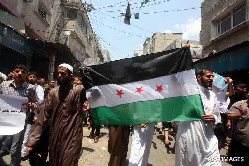Palestinians hold a Syrian revolution flag during a protest against Syria's President Bashar al-Assad and in support of Syrian civilians at Nusseirat refugee camp in the central Gaza Strip on June 22, 2012. The French fo...