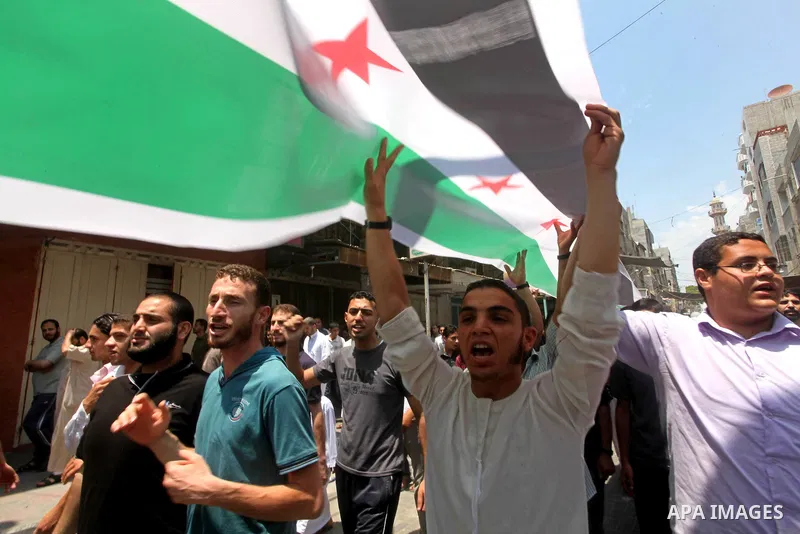 Palestinians hold a Syrian revolution flag during a protest against Syria's President Bashar al-Assad and in support of Syrian civilians at Nusseirat refugee camp in the central Gaza Strip on June 22, 2012. The French fo...