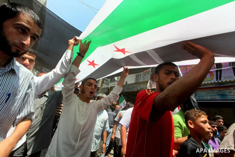 Palestinians hold a Syrian revolution flag during a protest against Syria's President Bashar al-Assad and in support of Syrian civilians at Nusseirat refugee camp in the central Gaza Strip on June 22, 2012. The French fo...