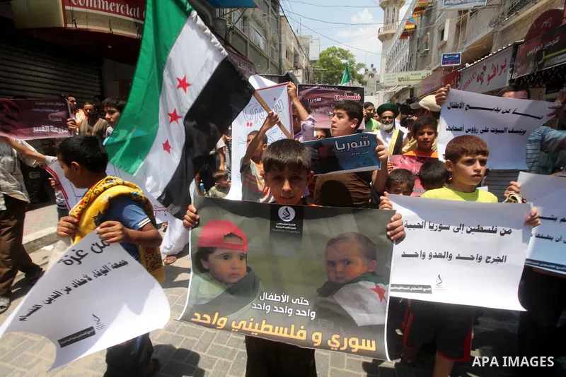 Palestinian children hold a Syrian revolution flag during a protest against Syria's President Bashar al-Assad and in support of Syrian civilians at Nusseirat refugee camp in the central Gaza Strip on June 22, 2012. The F...
