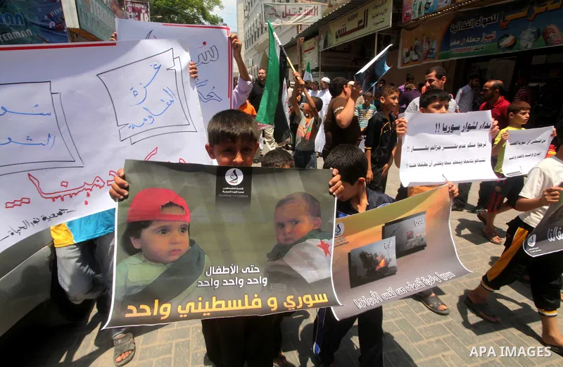 Palestinian children hold a Syrian revolution flag during a protest against Syria's President Bashar al-Assad and in support of Syrian civilians at Nusseirat refugee camp in the central Gaza Strip on June 22, 2012. The F...