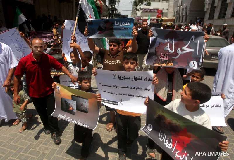 Palestinian children hold a Syrian revolution flag during a protest against Syria's President Bashar al-Assad and in support of Syrian civilians at Nusseirat refugee camp in the central Gaza Strip on June 22, 2012. The F...