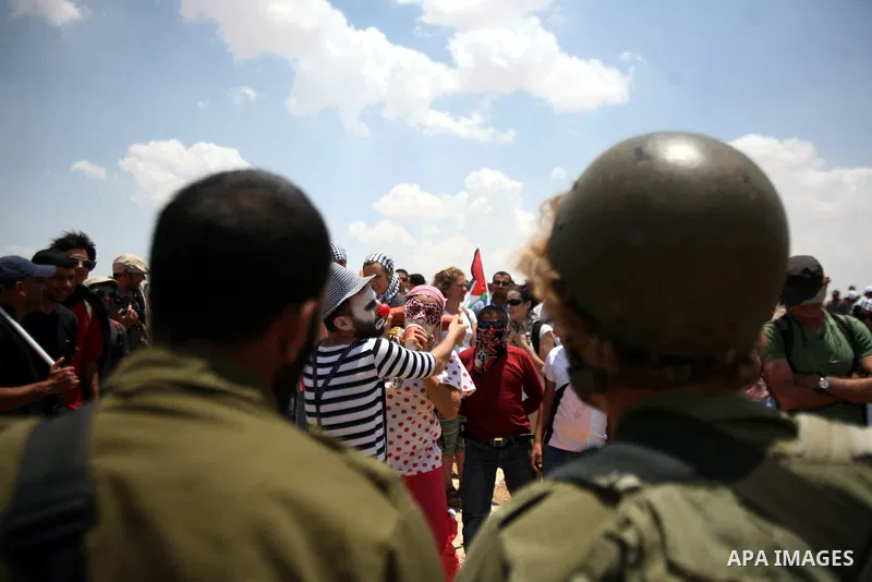 Foreign activists and Palestinians dressed as clowns gesture in front of Israeli policemen during a protest in the southern West Bank village of Susia near Hebron city on June 22, 2012 where Israel has recently served or...