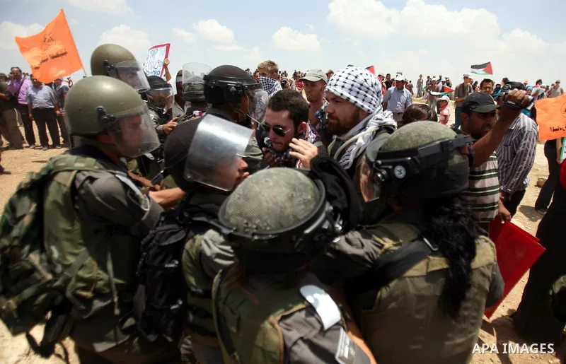 Foreign activists and Palestinians dressed as clowns gesture in front of Israeli policemen during a protest in the southern West Bank village of Susia near Hebron city on June 22, 2012 where Israel has recently served or...
