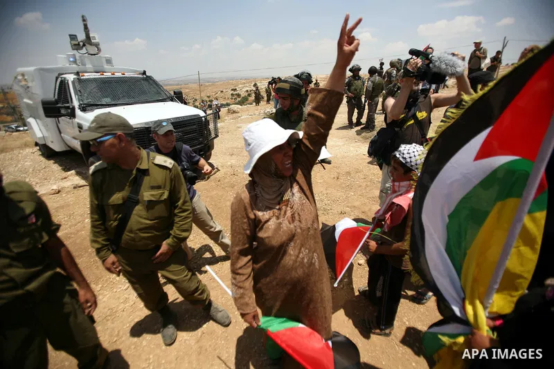 Foreign activists and Palestinians dressed as clowns gesture in front of Israeli policemen during a protest in the southern West Bank village of Susia near Hebron city on June 22, 2012 where Israel has recently served or...