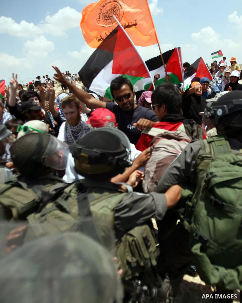Foreign activists and Palestinians dressed as clowns gesture in front of Israeli policemen during a protest in the southern West Bank village of Susia near Hebron city on June 22, 2012 where Israel has recently served or...