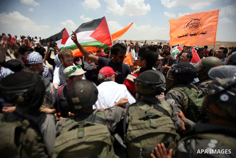 Foreign activists and Palestinians dressed as clowns gesture in front of Israeli policemen during a protest in the southern West Bank village of Susia near Hebron city on June 22, 2012 where Israel has recently served or...