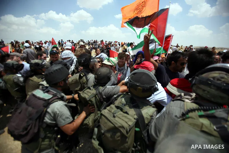 Foreign activists and Palestinians dressed as clowns gesture in front of Israeli policemen during a protest in the southern West Bank village of Susia near Hebron city on June 22, 2012 where Israel has recently served or...