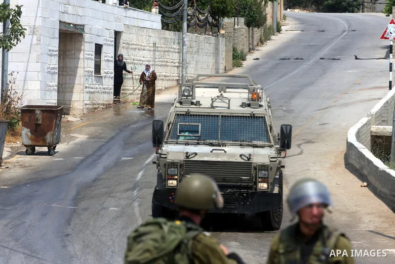 Palestinian women look at the Israeli soldiers during clashes with Palestinian protesters in the West Bank village of Nabi Saleh, near Ramallah, on June 22, 2012, following a demonstration against the confiscation of Pal...